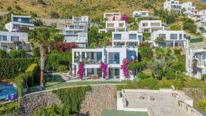 A hillside residential area with modern white houses, a swimming pool, and lush greenery. - Villa Matie Bodrum Views (Bodrum)