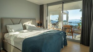 A bedroom with a large bed, a balcony with a table and chairs, and a view of the sea. - Villa Matie Bodrum Views (Bodrum)