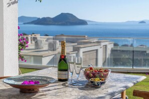 Ein Tisch mit einer Flasche Moët & Chandon Champagner, zwei Gläsern und einer Schale Erdbeeren auf einer Terrasse mit Meerblick.