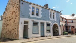 A two-story building with a mix of brick and plaster walls, a visible chimney, and a small front garden. - The Herring's Lean (Eyemouth)