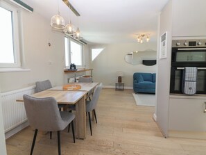 Eine moderne Küche mit Essbereich, einem blauen Sofa und Blick zum Wohnzimmer.