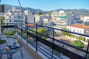 A balcony with a table, chairs, and a potted plant. - Cozy flat on the main square, 10min to the sea (Kalamata)