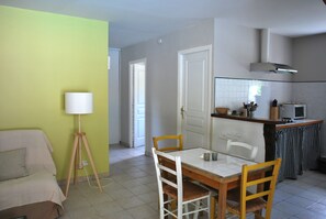 Un espace de vie compact comprenant un coin repas, une kitchenette et une porte donnant sur une autre pièce.