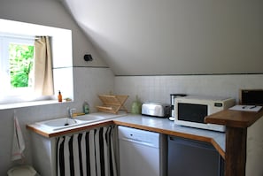 Eine kompakte Küche mit Fenster, Spüle, Geschirrspüler, Toaster und Mikrowelle.