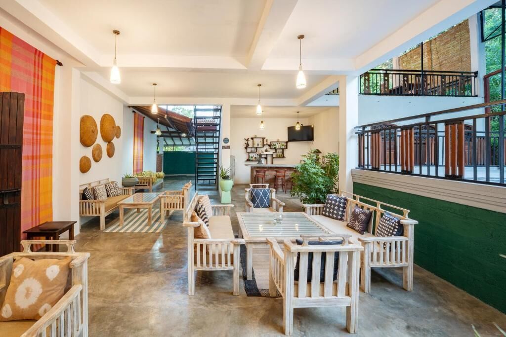Um interior espaçoso com área de estar central, escada e vista para o verde lá fora.