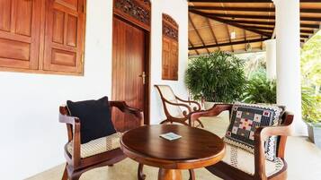 Une table en bois avec deux chaises, une grande porte en bois et un espace abrité avec des colonnes.
