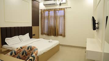 Habitación de hotel con cama, escritorio, televisor montado en la pared y aire acondicionado.