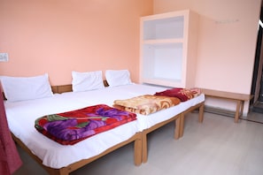 A single-bed room with a wooden frame, white bedding, and a colorful blanket.