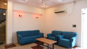 A room with a blue sofa, a matching armchair, and a wooden table. - Shree Krishna Hotel & Restaurant (Sakrai)