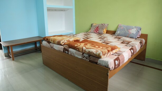 A single-bed room with a wooden frame, a bench, and a built-in wardrobe. - Shree Krishna Hotel & Restaurant (Sakrai)