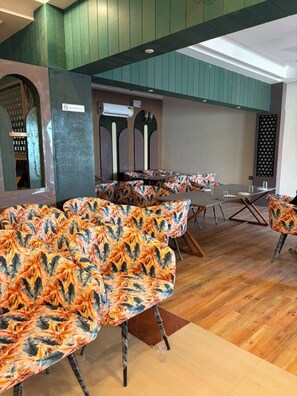 Interior de restaurante con techos altos, paredes verdes y un letrero que dice 'No Smoking'.