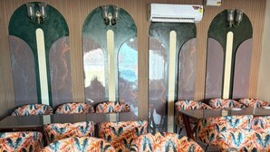 A restaurant with a long communal table and multiple booths with floral upholstery. - Shree Krishna Hotel & Restaurant (Sakrai)