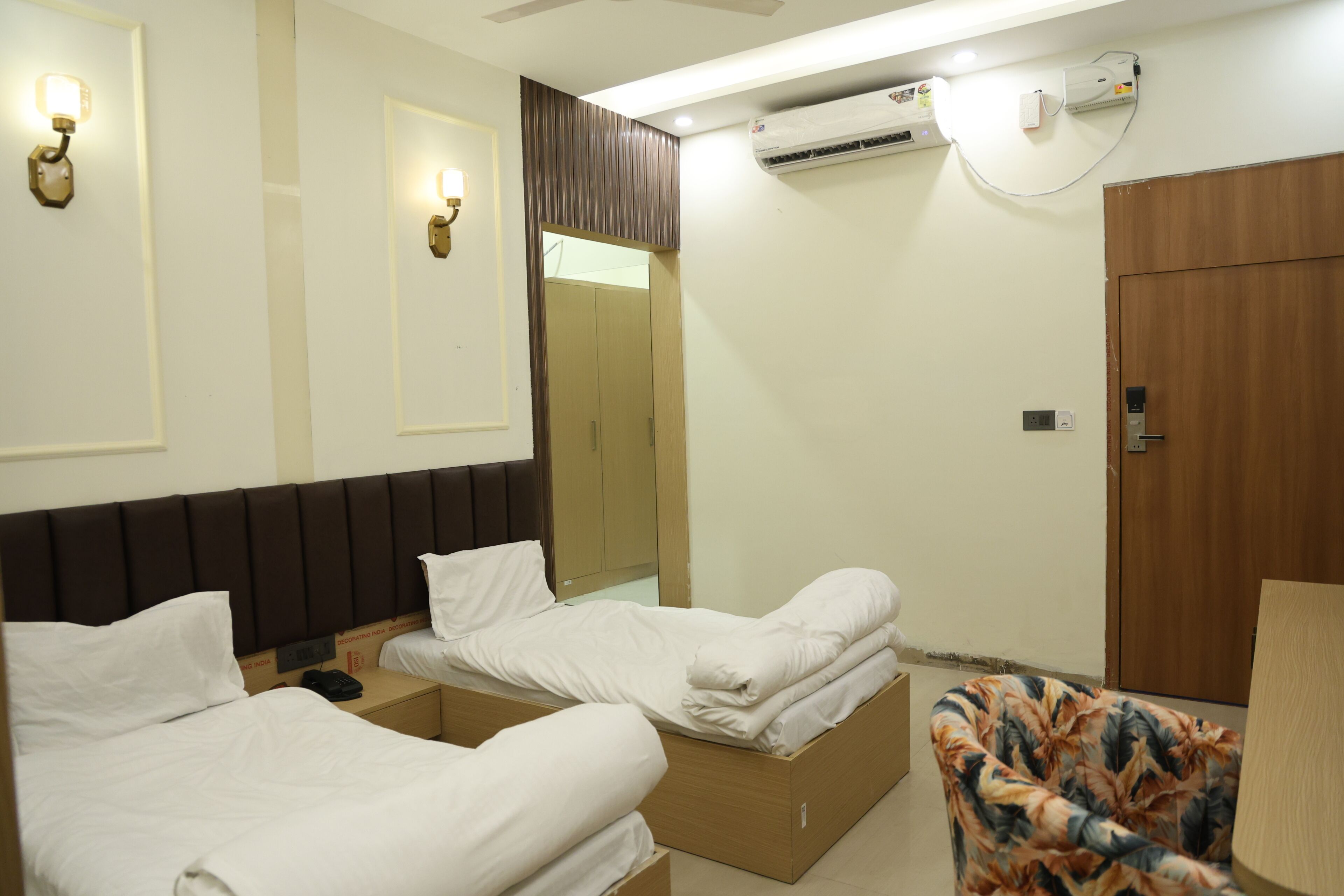 Une chambre d’hôtel avec deux lits, une armoire, un appareil de climatisation et un téléphone sur la table de chevet.