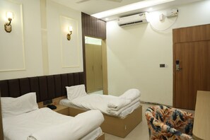 Habitación de hotel con dos camas, un armario, un equipo de aire acondicionado y un teléfono en la mesita de noche.