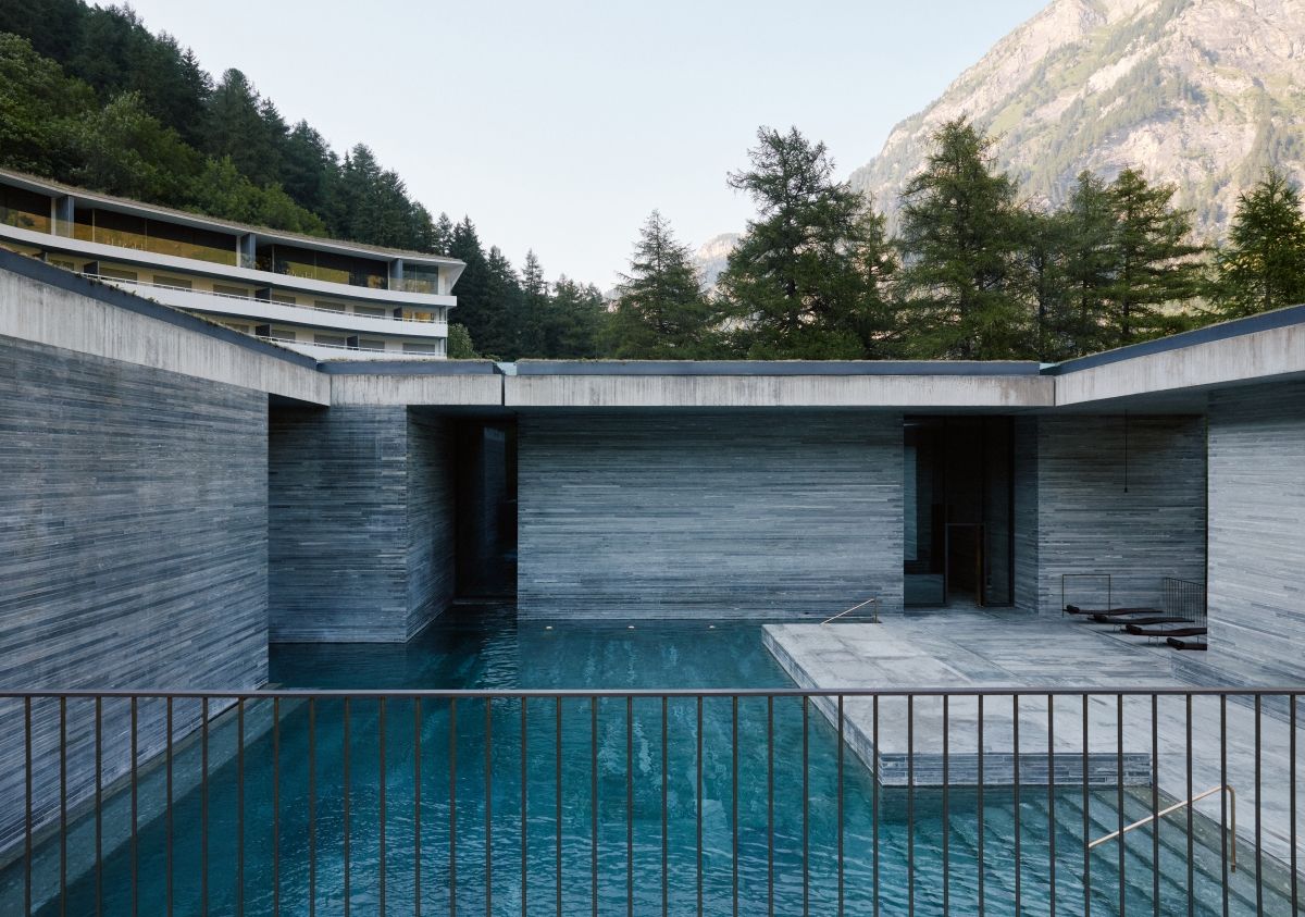 Ein modernes Gebäude mit Pool, umgeben von Bäumen und Bergen.