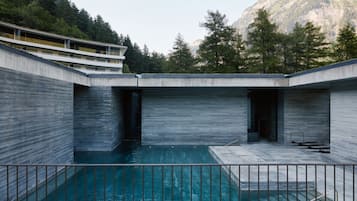 Ein modernes Gebäude mit Pool, umgeben von Bäumen und Bergen.