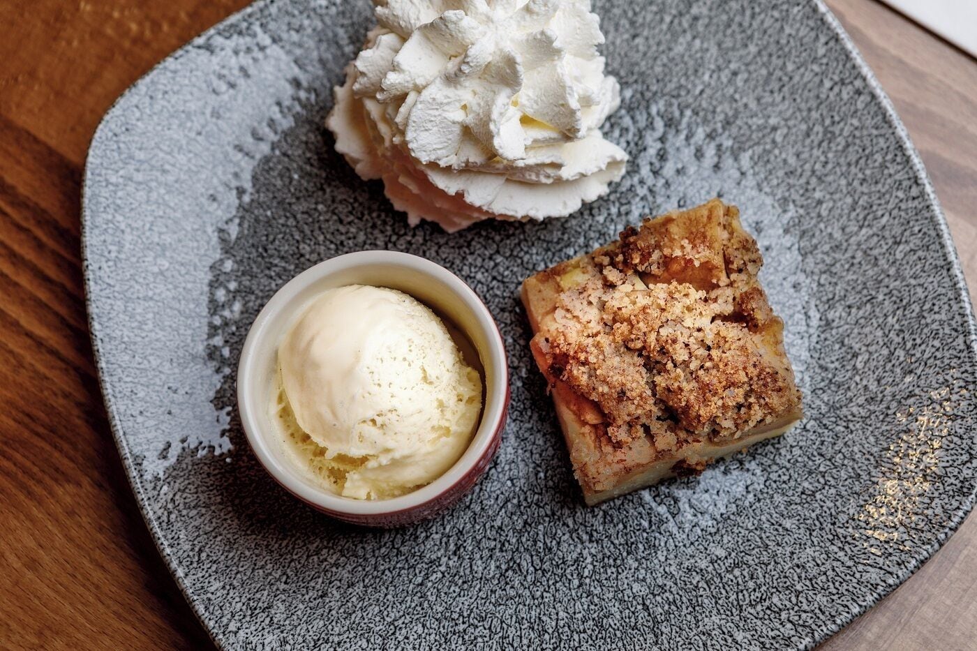A dessert plate with a scoop of ice cream and a crumbly pastry.