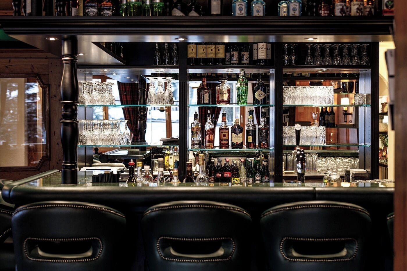 Een bar met meerdere flessen drank, glazen en een bargedeelte.