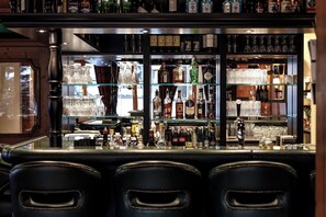 A bar area with multiple shelves of liquor bottles, glasses, and a bar counter.