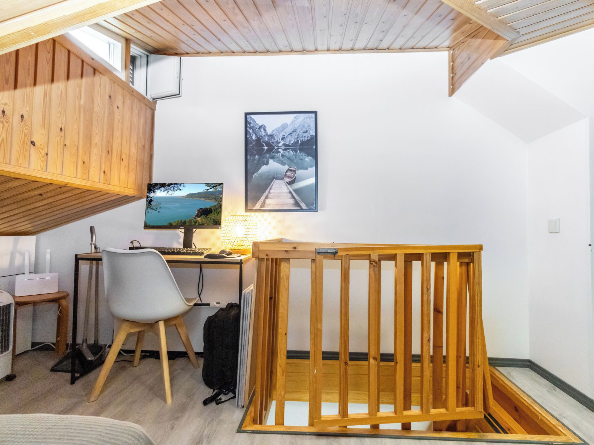 Huoneessa on puinen työpöytä, tietokone, tuoli, puurunkoon rakennettu sänky, ikkuna ja seinälle ripustettu taulu.
