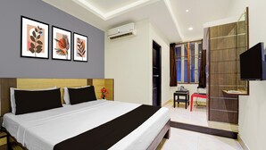 A hotel room with a large bed, a flat-screen TV, a desk with a chair, and a window with curtains. - Collection O Thiruparankundram City (Madurai)