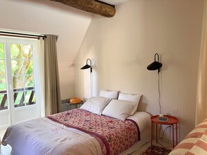 Ein Schlafzimmer mit einem Bett, zwei Nachttischlampen, einem Nachttisch mit einer Uhr und einem Fenster mit Vorhängen.