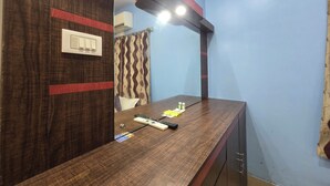 Un baño con tocador de madera, un espejo, toallero y cortina de ducha.