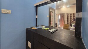Una habitación con una pared azul, un armario de madera con espejo y una puerta que da a otra estancia.