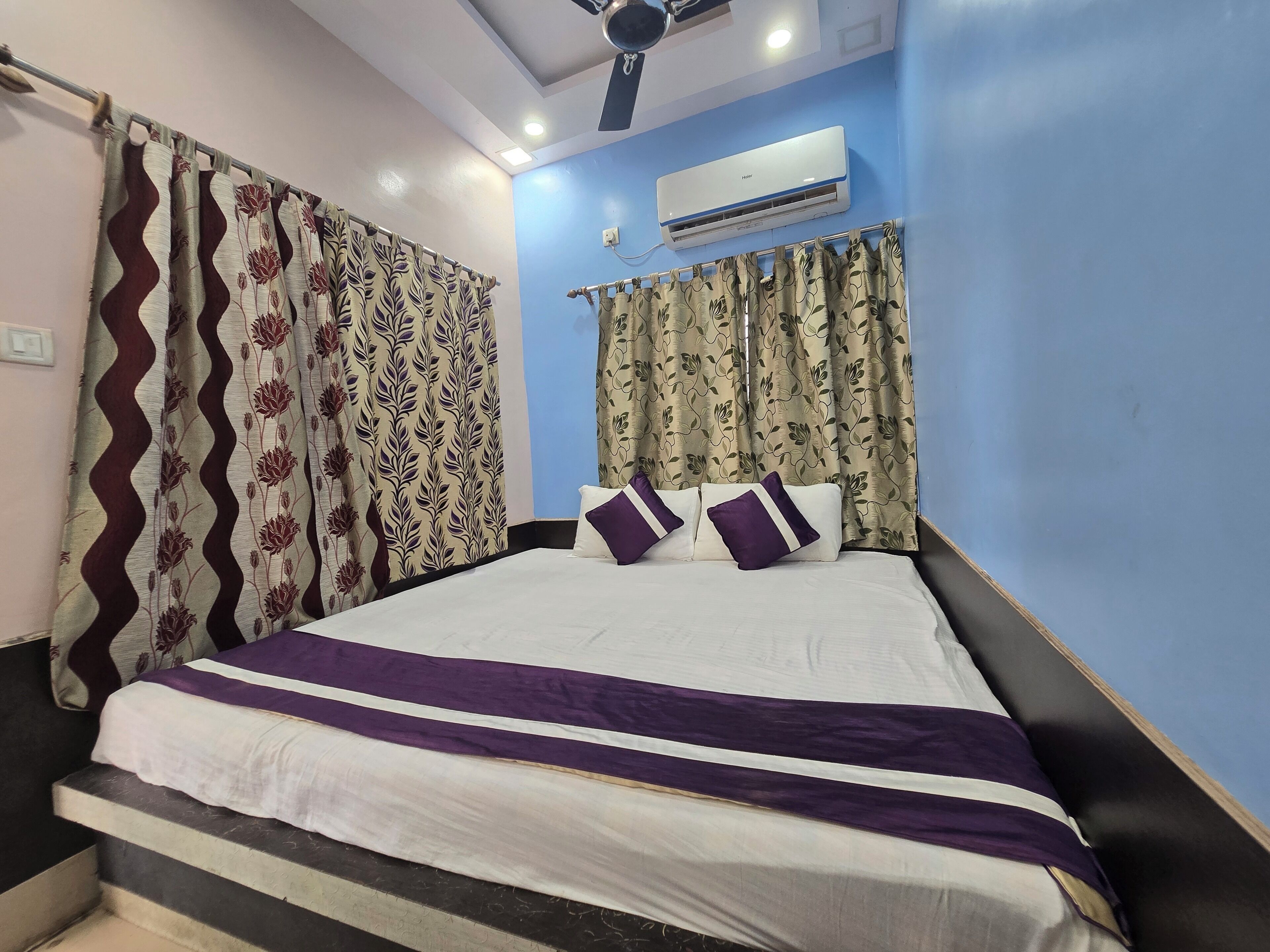 Un dormitorio con cama, cortinas, equipo de aire acondicionado y ventilador de techo.