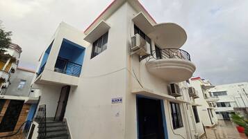 A multi-story residential building with a balcony, a staircase, and a checkered floor pattern.