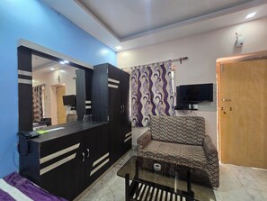 Una habitación con sofá, televisión, armario y espejo.