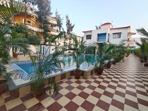 Zona de piscina en la azotea con plantas en macetas y suelo a cuadros.
