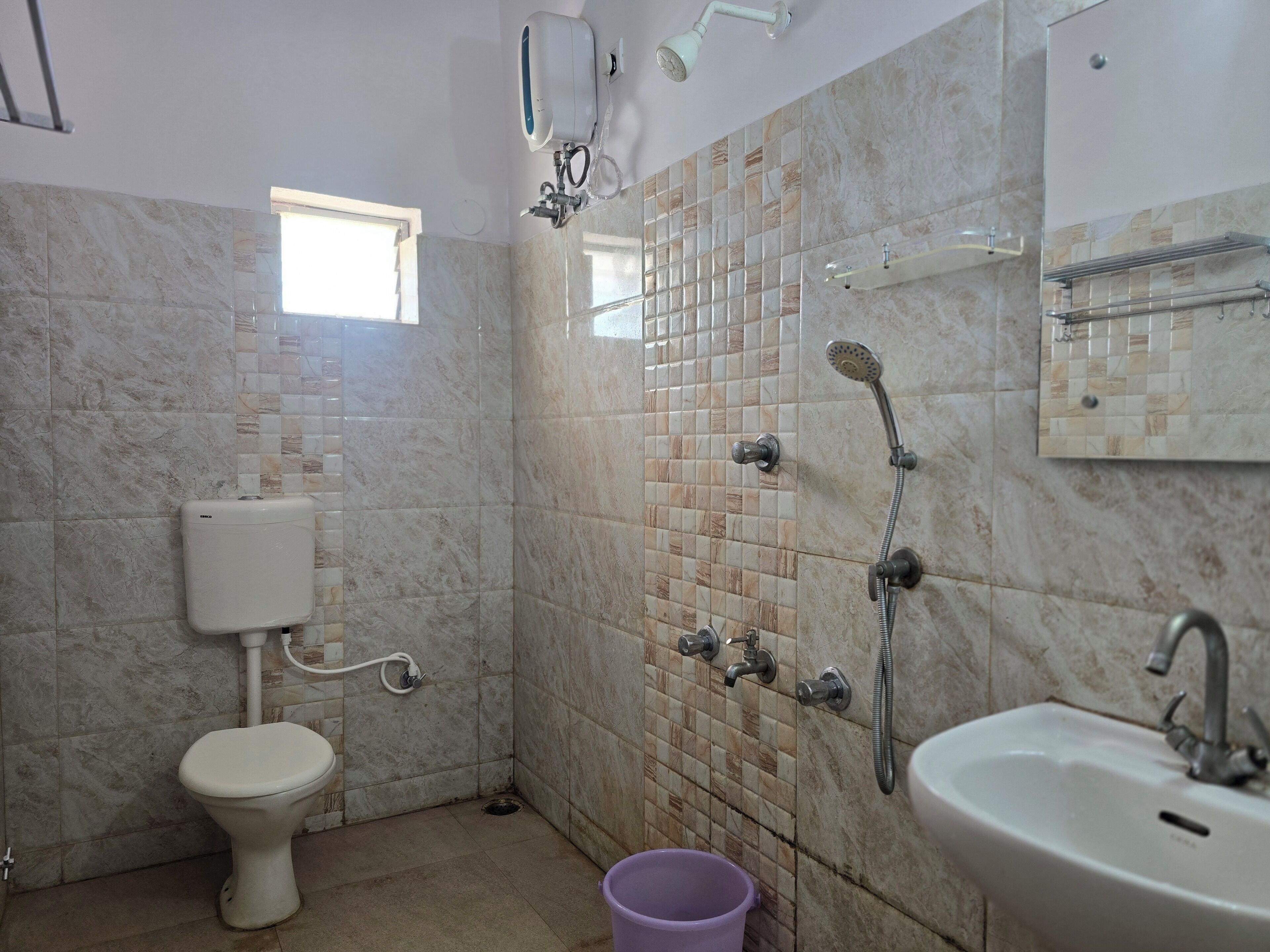 Baño con inodoro, lavamanos, ducha y paredes con azulejos.