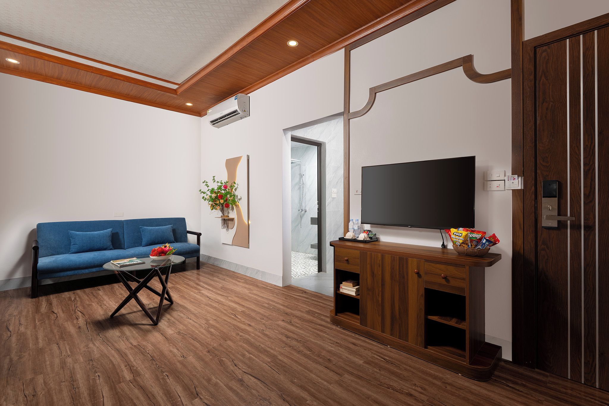 Una sala de estar moderna con un sofá azul, una mesa de centro, un mueble de entretenimiento de madera y un televisor de pantalla plana.
