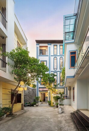 Un patio con un edificio de fachada azul y un letrero que dice 'NOC CHERRY'.