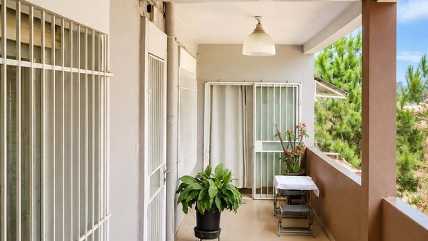 A balcony with a tiled floor, a potted plant, a table with a chair, and a view of greenery. - TranoBe – Spacious, bright loft in Antananarivo, near downtown (Tananarive)