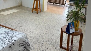 A room with a bed, a small stool, a table with a plant, a TV, and a bench. - TranoBe – Spacious, bright loft in Antananarivo, near downtown (Tananarive)