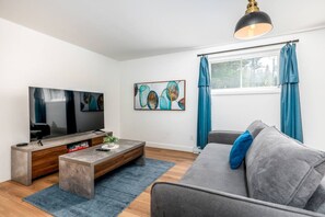Ein modernes Wohnzimmer mit Flachbildfernseher, einer Couch, einem Couchtisch und Kunstwerken an den Wänden.