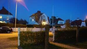Ett bostadsområde med hus, en asfalterad väg och en bil parkerad vid vägkanten.