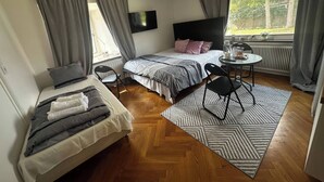 Ett litet sovrum med en säng, ett skrivbord, en stol och ett litet bord.