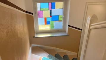 Eine Treppe mit Teppich und einem Fenster mit farbigen Glasfeldern.