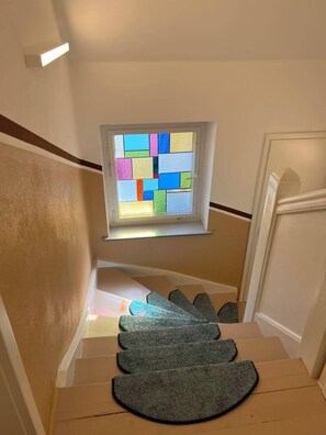 A staircase with a carpet and a window with colorful glass panes. - Pension Kugelblitz—Modern 2-Bedroom Apartment (Grimma)