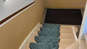 A staircase with a carpeted landing and a light fixture above.