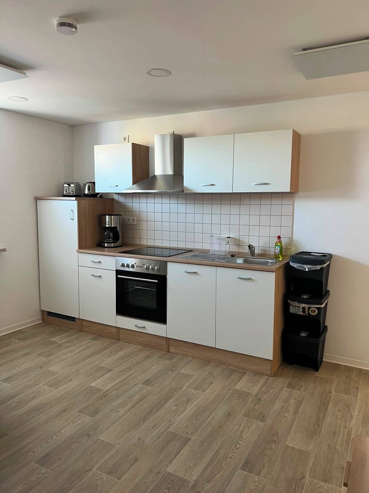 Une cuisine moderne avec des armoires blanches, une cuisinière en acier inoxydable et un four encastré.