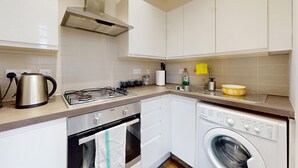 Una cucina compatta con piano cottura a gas, bollitore e lavatrice integrata.