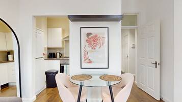 A modern kitchen with white cabinets, a black trash bin, and a coffee maker on the counter.
