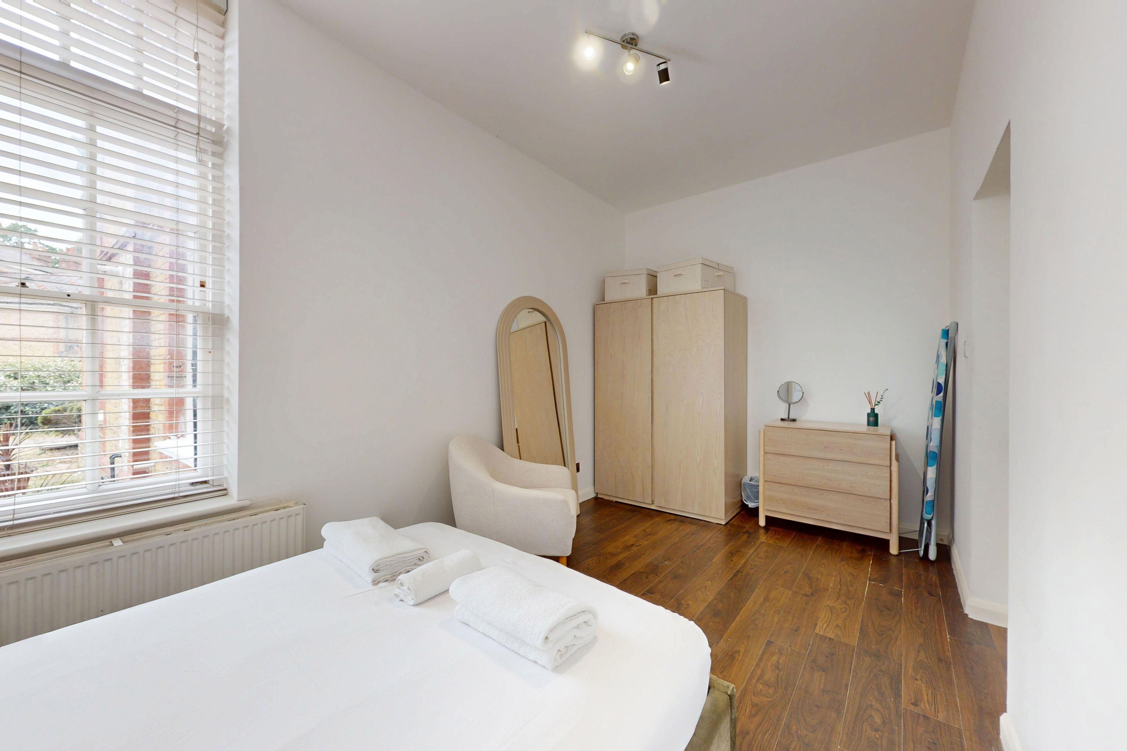 A bedroom with a bed, a wardrobe, a dresser, and a mirror.