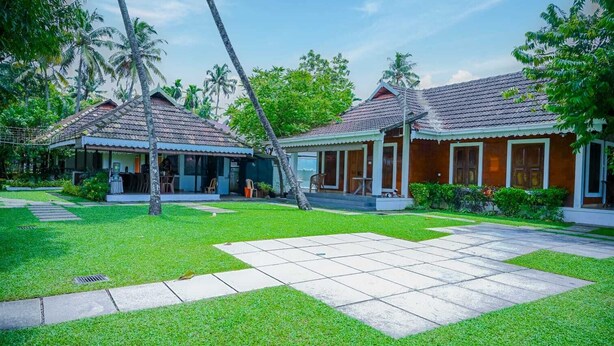 A resort with two buildings, each with a covered patio and a lawn in front. - Kochi Riverside Homestay (Kanayannur)