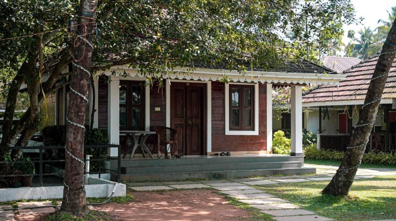 A two-story building with a porch, a staircase leading to the entrance, and a small outdoor seating area.