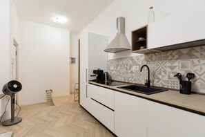 A modern kitchen with a herringbone floor pattern, a built-in stove, a sink, and a ventilation hood. - A comfortable 73 sqm apartment, ideal for 6 people, located on the lower ground floor of a building with an elevator.The apartment enjoys a strategic location, just 450 meters from the “Porta Romana” stop on the M3 (Yellow) metro line, which takes yo (Milan)